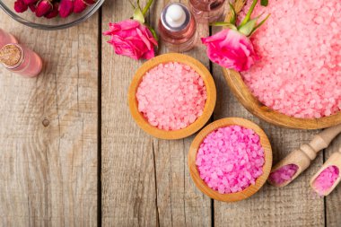 Banyo için deniz tuzu aromalı ve ahşap kaplamalı gül çiçekli. Pembe deniz tuzu. Spa tedavileri. Doğal tuz, bitkiler ve gerekli yağlar. Cilt bakımı. Mesaj için Meso. Boşluğu kopyala