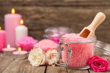 Banyo için deniz tuzu aromalı ve ahşap kaplamalı gül çiçekli. Pembe deniz tuzu. Spa tedavileri. Doğal tuz, bitkiler ve gerekli yağlar. Cilt bakımı. Mesaj için Meso. Boşluğu kopyala