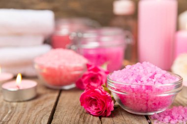 Banyo için deniz tuzu aromalı ve ahşap kaplamalı gül çiçekli. Pembe deniz tuzu. Spa tedavileri. Doğal tuz, bitkiler ve gerekli yağlar. Cilt bakımı. Mesaj için Meso. Boşluğu kopyala