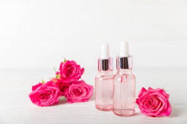 Arka planda gül yağı. Güller ve bir şişe parfümlü su. Romaterapi tedavisi. Güzellik konsepti. Spa prosedürü. Doğal organik yağ. Stres önleyici, detoks gevşetici.