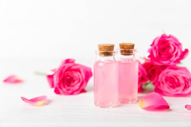 Arka planda gül yağı. Güller ve bir şişe parfümlü su. Romaterapi tedavisi. Güzellik konsepti. Spa prosedürü. Doğal organik yağ. Stres önleyici, detoks gevşetici.