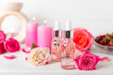 Arka planda gül yağı. Güller ve bir şişe parfümlü su. Romaterapi tedavisi. Güzellik konsepti. Spa prosedürü. Doğal organik yağ. Stres önleyici, detoks gevşetici.