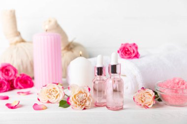Arka planda gül yağı. Güller ve bir şişe parfümlü su. Romaterapi tedavisi. Güzellik konsepti. Spa prosedürü. Doğal organik yağ. Stres önleyici, detoks gevşetici.