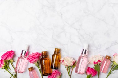 Arka planda gül yağı. Güller ve bir şişe parfümlü su. Romaterapi tedavisi. Güzellik konsepti. Spa prosedürü. Doğal organik yağ. Stres önleyici, detoks gevşetici.