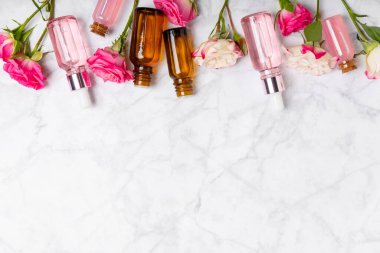Arka planda gül yağı. Güller ve bir şişe parfümlü su. Romaterapi tedavisi. Güzellik konsepti. Spa prosedürü. Doğal organik yağ. Stres önleyici, detoks gevşetici.