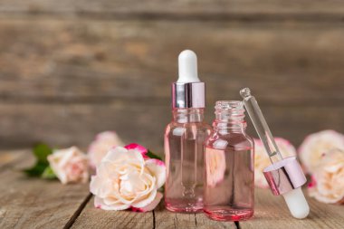 Arka planda gül yağı. Güller ve bir şişe parfümlü su. Romaterapi tedavisi. Güzellik konsepti. Spa prosedürü. Doğal organik yağ. Stres önleyici, detoks gevşetici.