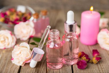 Arka planda gül yağı. Güller ve bir şişe parfümlü su. Romaterapi tedavisi. Güzellik konsepti. Spa prosedürü. Doğal organik yağ. Stres önleyici, detoks gevşetici.