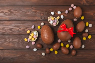 Arka planda paskalya çikolatalı yumurtası. Paskalya kutlaması. Paskalya çikolatalı tavşan. Çikolatalı tatlı yumurta. Şekerler ahşap masanın üzerinde. Mesaj için boşluk. Boşluğu kopyala. Hediye. Pankart.