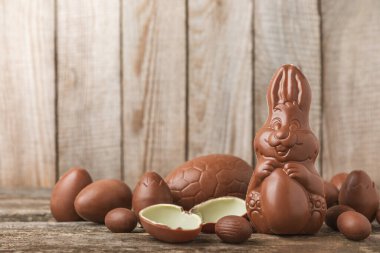 Arka planda paskalya çikolatalı yumurtası. Paskalya kutlaması. Paskalya çikolatalı tavşan. Çikolatalı tatlı yumurta. Şekerler ahşap masanın üzerinde. Mesaj için boşluk. Boşluğu kopyala. Hediye. Pankart.