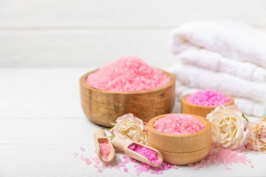Banyo için deniz tuzu aromalı ve ahşap kaplamalı gül çiçekli. Pembe deniz tuzu. Spa tedavileri. Doğal tuz, bitkiler ve gerekli yağlar. Cilt bakımı. Mesaj için Meso. Boşluğu kopyala