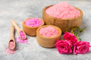 Banyo için deniz tuzu aromalı ve ahşap kaplamalı gül çiçekli. Pembe deniz tuzu. Spa tedavileri. Doğal tuz, bitkiler ve gerekli yağlar. Cilt bakımı. Mesaj için Meso. Boşluğu kopyala