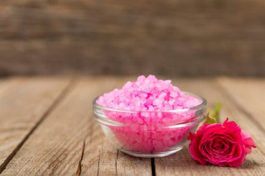 Banyo için deniz tuzu aromalı ve ahşap kaplamalı gül çiçekli. Pembe deniz tuzu. Spa tedavileri. Doğal tuz, bitkiler ve gerekli yağlar. Cilt bakımı. Mesaj için Meso. Boşluğu kopyala
