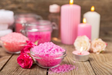 Banyo için deniz tuzu aromalı ve ahşap kaplamalı gül çiçekli. Pembe deniz tuzu. Spa tedavileri. Doğal tuz, bitkiler ve gerekli yağlar. Cilt bakımı. Mesaj için Meso. Boşluğu kopyala