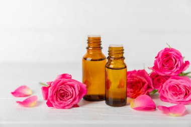 Arka planda gül yağı. Güller ve bir şişe parfümlü su. Romaterapi tedavisi. Güzellik konsepti. Spa prosedürü. Doğal organik yağ. Stres önleyici, detoks gevşetici.