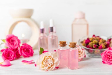 Arka planda gül yağı. Güller ve bir şişe parfümlü su. Romaterapi tedavisi. Güzellik konsepti. Spa prosedürü. Doğal organik yağ. Stres önleyici, detoks gevşetici.