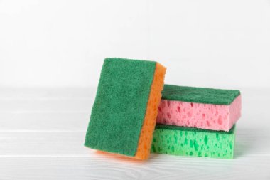 Arka planda renkli bulaşık süngerleri. Mutfak süngeri. Temizlik konsepti, temizlik hizmeti. Bulaşık deterjanı ve temiz ve kirli tabaklar. Metin için yer, kopyalama alanı. Bulaşıkları yıka..