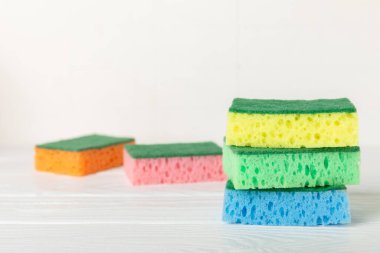 Arka planda renkli bulaşık süngerleri. Mutfak süngeri. Temizlik konsepti, temizlik hizmeti. Bulaşık deterjanı ve temiz ve kirli tabaklar. Metin için yer, kopyalama alanı. Bulaşıkları yıka..