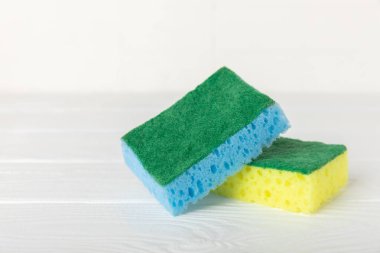 Arka planda renkli bulaşık süngerleri. Mutfak süngeri. Temizlik konsepti, temizlik hizmeti. Bulaşık deterjanı ve temiz ve kirli tabaklar. Metin için yer, kopyalama alanı. Bulaşıkları yıka..