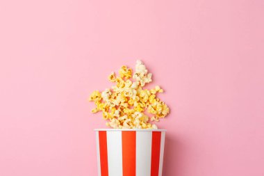 Patlamış mısır kutusu. Renkli arka planda kırmızı ve beyaz çizgili patlamış mısır kovaları. Sinema ve eğlence anlayışı. Patlamış mısırla film gecesi. Lezzetli aperatif, aperatif. Metin için yer.