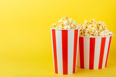 Patlamış mısır kutusu. Renkli arka planda kırmızı ve beyaz çizgili patlamış mısır kovaları. Sinema ve eğlence anlayışı. Patlamış mısırla film gecesi. Lezzetli aperatif, aperatif. Metin için yer.