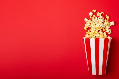 Patlamış mısır kutusu. Renkli arka planda kırmızı ve beyaz çizgili patlamış mısır kovaları. Sinema ve eğlence anlayışı. Patlamış mısırla film gecesi. Lezzetli aperatif, aperatif. Metin için yer.