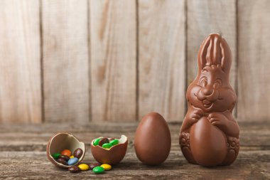 Arka planda paskalya çikolatalı yumurtası. Paskalya kutlaması. Paskalya çikolatalı tavşan. Çikolatalı tatlı yumurta. Şekerler ahşap masanın üzerinde. Mesaj için boşluk. Boşluğu kopyala. Hediye. Pankart.