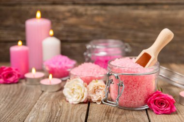 Banyo için deniz tuzu aromalı ve ahşap kaplamalı gül çiçekli. Pembe deniz tuzu. Spa tedavileri. Doğal tuz, bitkiler ve gerekli yağlar. Cilt bakımı. Mesaj için Meso. Boşluğu kopyala