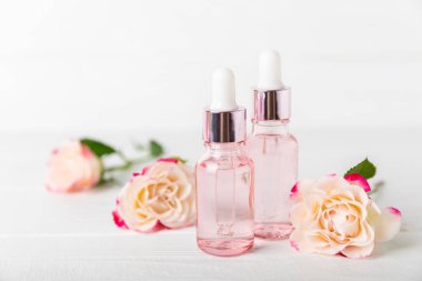 Arka planda gül yağı. Güller ve bir şişe parfümlü su. Romaterapi tedavisi. Güzellik konsepti. Spa prosedürü. Doğal organik yağ. Stres önleyici, detoks gevşetici.