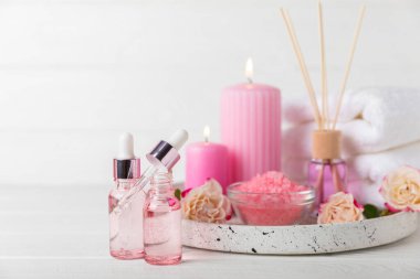 Arka planda gül yağı. Güller ve bir şişe parfümlü su. Romaterapi tedavisi. Güzellik konsepti. Spa prosedürü. Doğal organik yağ. Stres önleyici, detoks gevşetici.