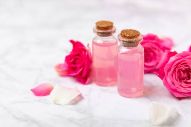 Arka planda gül yağı. Güller ve bir şişe parfümlü su. Romaterapi tedavisi. Güzellik konsepti. Spa prosedürü. Doğal organik yağ. Stres önleyici, detoks gevşetici.