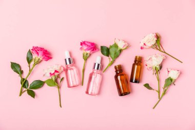 Arka planda gül yağı. Güller ve bir şişe parfümlü su. Romaterapi tedavisi. Güzellik konsepti. Spa prosedürü. Doğal organik yağ. Stres önleyici, detoks gevşetici.