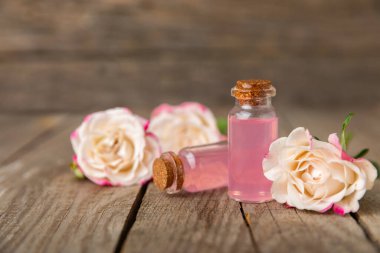 Arka planda gül yağı. Güller ve bir şişe parfümlü su. Romaterapi tedavisi. Güzellik konsepti. Spa prosedürü. Doğal organik yağ. Stres önleyici, detoks gevşetici.