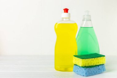 Arka planda renkli bulaşık süngerleri. Mutfak süngeri. Temizlik konsepti, temizlik hizmeti. Bulaşık deterjanı ve temiz ve kirli tabaklar. Metin için yer, kopyalama alanı. Bulaşıkları yıka..