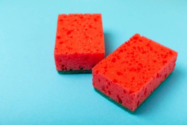 Arka planda renkli bulaşık süngerleri. Mutfak süngeri. Temizlik konsepti, temizlik hizmeti. Bulaşık deterjanı ve temiz ve kirli tabaklar. Metin için yer, kopyalama alanı. Bulaşıkları yıka..