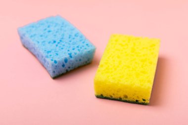 Arka planda renkli bulaşık süngerleri. Mutfak süngeri. Temizlik konsepti, temizlik hizmeti. Bulaşık deterjanı ve temiz ve kirli tabaklar. Metin için yer, kopyalama alanı. Bulaşıkları yıka..