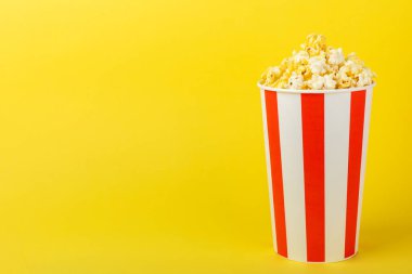 Patlamış mısır kutusu. Renkli arka planda kırmızı ve beyaz çizgili patlamış mısır kovaları. Sinema ve eğlence anlayışı. Patlamış mısırla film gecesi. Lezzetli aperatif, aperatif. Metin için yer.