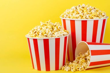 Patlamış mısır kutusu. Renkli arka planda kırmızı ve beyaz çizgili patlamış mısır kovaları. Sinema ve eğlence anlayışı. Patlamış mısırla film gecesi. Lezzetli aperatif, aperatif. Metin için yer.