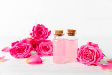 Arka planda gül yağı. Güller ve bir şişe parfümlü su. Romaterapi tedavisi. Güzellik konsepti. Spa prosedürü. Doğal organik yağ. Stres önleyici, detoks gevşetici.