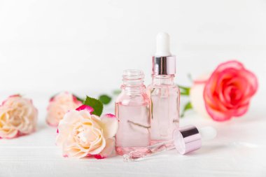 Arka planda gül yağı. Güller ve bir şişe parfümlü su. Romaterapi tedavisi. Güzellik konsepti. Spa prosedürü. Doğal organik yağ. Stres önleyici, detoks gevşetici.