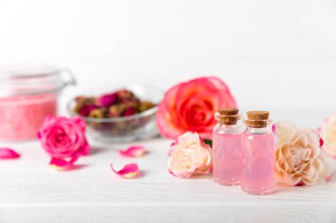 Arka planda gül yağı. Güller ve bir şişe parfümlü su. Romaterapi tedavisi. Güzellik konsepti. Spa prosedürü. Doğal organik yağ. Stres önleyici, detoks gevşetici.