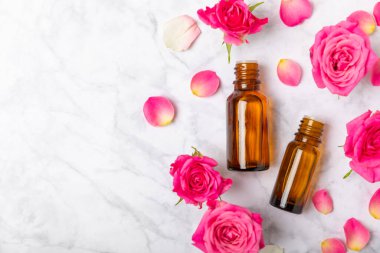 Arka planda gül yağı. Güller ve bir şişe parfümlü su. Romaterapi tedavisi. Güzellik konsepti. Spa prosedürü. Doğal organik yağ. Stres önleyici, detoks gevşetici.