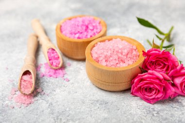 Banyo için deniz tuzu aromalı ve ahşap kaplamalı gül çiçekli. Pembe deniz tuzu. Spa tedavileri. Doğal tuz, bitkiler ve gerekli yağlar. Cilt bakımı. Mesaj için Meso. Boşluğu kopyala