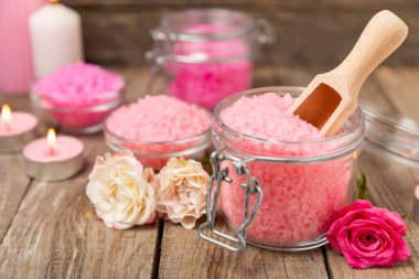 Banyo için deniz tuzu aromalı ve ahşap kaplamalı gül çiçekli. Pembe deniz tuzu. Spa tedavileri. Doğal tuz, bitkiler ve gerekli yağlar. Cilt bakımı. Mesaj için Meso. Boşluğu kopyala