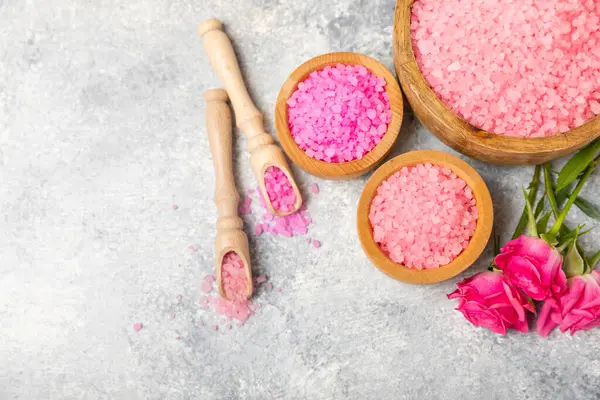 Banyo için deniz tuzu aromalı ve ahşap kaplamalı gül çiçekli. Pembe deniz tuzu. Spa tedavileri. Doğal tuz, bitkiler ve gerekli yağlar. Cilt bakımı. Mesaj için Meso. Boşluğu kopyala