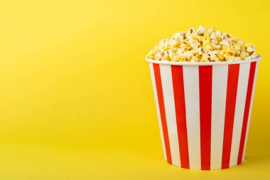 Patlamış mısır kutusu. Renkli arka planda kırmızı ve beyaz çizgili patlamış mısır kovaları. Sinema ve eğlence anlayışı. Patlamış mısırla film gecesi. Lezzetli aperatif, aperatif. Metin için yer.