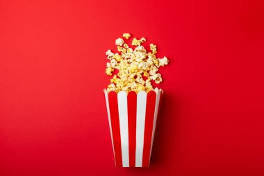 Patlamış mısır kutusu. Renkli arka planda kırmızı ve beyaz çizgili patlamış mısır kovaları. Sinema ve eğlence anlayışı. Patlamış mısırla film gecesi. Lezzetli aperatif, aperatif. Metin için yer.