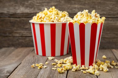 Patlamış mısır kutusu. Renkli arka planda kırmızı ve beyaz çizgili patlamış mısır kovaları. Sinema ve eğlence anlayışı. Patlamış mısırla film gecesi. Lezzetli aperatif, aperatif. Metin için yer.