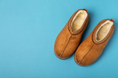 Açık renkli arka planda yumuşak terlikler, yakın plan. Ev terlikleri. Ev için rahat ayakkabılar. Ayak bakımı konsepti. Ev rahatlığı. Mesaj için yer var. Boşluğu kopyala.