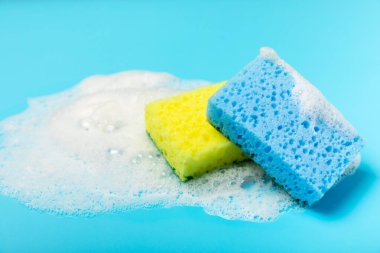 Arka planda renkli bulaşık süngerleri. Mutfak süngeri. Temizlik konsepti, temizlik hizmeti. Bulaşık deterjanı ve temiz ve kirli tabaklar. Metin için yer, kopyalama alanı. Bulaşıkları yıka..