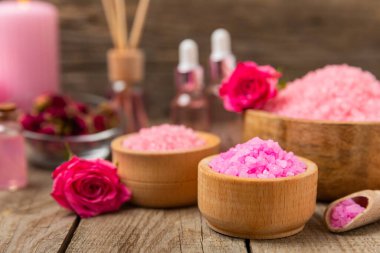Banyo için deniz tuzu aromalı ve ahşap kaplamalı gül çiçekli. Pembe deniz tuzu. Spa tedavileri. Doğal tuz, bitkiler ve gerekli yağlar. Cilt bakımı. Mesaj için Meso. Boşluğu kopyala